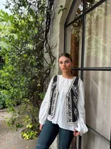 Chaleco negro con bordados florales blancos y ribete de crochet.