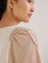 Remera gris de algodón con mangas color beige con bordados de líneas en blanco, amarillo y gris.