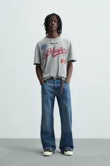 Camiseta gris con cuello redondo y manga corta. Presenta estampados, bordados y parches frontales combinados a contraste. Tiene un efecto lavado.