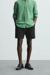 Bermuda de algodón color marrón oscuro, de corte regular fit, con cintura elástica ajustable mediante cordón. Presenta bolsillos laterales y un bolsillo trasero de vivo.