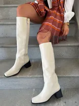 Bota alta color hueso, con caña recta, punta cuadrada y taco bloque negro.