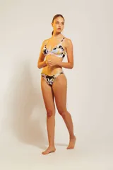 Conjunto de bikini de dos piezas con corpiño triangular negro con tirantes finos y detalle de contorno en color beige. La bombacha es de corte clásico en color beige.