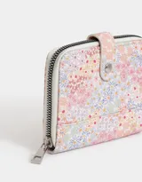 Billetera de cuerina color blanco con estampado de cerezas, frutillas y flores. Tiene cierre circundante y solapa con broche a presión. Cuenta con compartimentos para tarjetas y billetes.