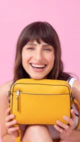 Bandolera color beige con diseño geométrico en el frente, cierre superior y correa larga regulable.