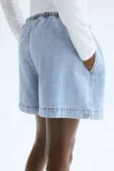 Short holgado de denim celeste con cintura elastizada y cordón de ajuste.