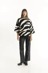 Sweater color crema con cuello alto y mangas cortas anchas, con diseño de cuadros negros.