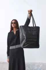 Bolso tipo shopper de cuero negro con acabado laminado brillante.