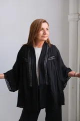 Kimono negro con detalles de encaje en los bordes y mangas anchas.