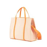 Cartera tipo shopper color naranja y beige, con detalles en símil cuero, acceso con cierre, correa regulable y asa fija. Cuenta con un bolsillo externo con cierre, un bolsillo interno con cierre y dos bolsillos internos abiertos.