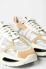 Zapatillas deportivas de malla blanca con superposiciones de cuero color beige y verde. Suela gruesa de goma color hueso.