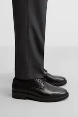 Zapato de vestir tipo derby de cuero negro, con puntera lisa, horma redonda y suela con ligero tacón.
