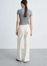 Pantalón de vestir color crema de corte palazzo, con pinzas en la cintura y cinturón fino con hebilla plateada.