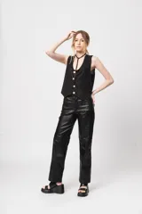 Pantalón de tiro alto negro de gabardina strech metalizada, con bolsillos y cierre frontal con cremallera y botón.