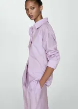 Camisa oversize lila con rayas verticales, de manga larga con puños abotonados, cuello camisero y dos bolsillos de parche en el pecho.
