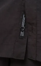 Camisa negra de manga corta con doble bolsillo ojal en delantero, realizada en tejido plano y silueta oversize.
