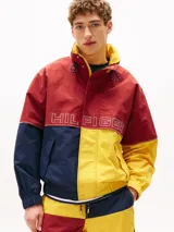 Campera de nailon con diseño color block en rojo, amarillo y azul marino. Tiene cuello alto, cierre de cremallera oculto con botones a presión, puños y bajo elásticos, dos bolsillos ribeteados en la cintura y logo de Tommy Hilfiger en la parte delantera, la trasera y las mangas.