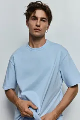 Remera celeste de corte holgado, cuello redondo ribeteado y mangas cortas. Confeccionada con tejido funcional COOLMAX®, una fibra de poliéster de secado rápido que elimina la humedad y regula la temperatura corporal.