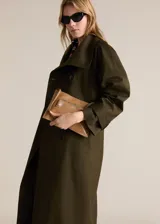 Trench coat verde militar con cuello solapa ancho, doble botonadura, cinturón desmontable, trabillas en cintura y puños, dos bolsillos laterales y forro interior.