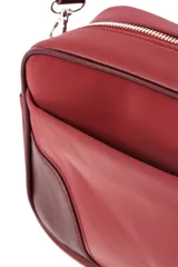 Bandolera rectangular color bordó, con correa larga regulable y detalles en cuero vegano color marrón oscuro en la base.