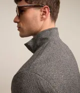 Buzo gris texturizado con cuello alto y cremallera delantera. Tiene mangas largas con puños ajustados, barra ajustada y dos bolsillos en el pecho con solapa y botón.