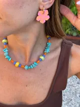 Collar corto con piedras turquesas irregulares, cuentas de cerámica amarillas y verdes, y cuentas plásticas naranjas y azules.