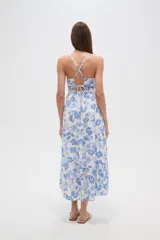 Vestido largo confeccionado en viscosa con estampado floral azul sobre fondo blanco. Posee escote en V, tirantes finos, cintura elástica y una abertura lateral profunda en la falda.