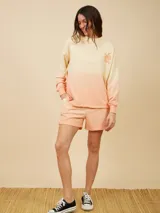 Sweater color crema con degradé a naranja, con cuello redondo y logo estampado de palmera en el pecho.