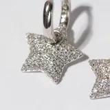 Par de aros tipo argolla con dije colgante en forma de estrella, recubiertos de circonitas.