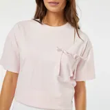 Camiseta rosa de manga corta con bolsillo en el pecho y lazos decorativos.