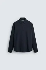 Camisa azul marino de corte regular fit, confeccionada en tejido de algodón con estructura. Tiene cuello solapa, manga larga con puños abotonados y cierre frontal con botones.