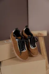 Championes marrones de cuero con cordones negros, puntera de charol y detalles dorados.