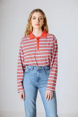 Remera de manga larga a rayas horizontales rojas, blancas y azules, con cuello polo rojo y tapeta con botones.