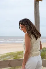 Chaleco tejido color crema, con cuello alto y sin mangas.