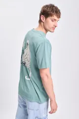 Remera verde de manga corta con corte oversize y estampa de un mono y la palabra 'Paradise' en la espalda.