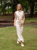 Conjunto color avena, compuesto por un top sin mangas con cuello camisero y nudo frontal, y un pantalón de corte recto.