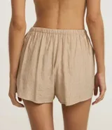 Short de playa suelto color beige, confeccionado en viscosa certificada, con cintura elástica ajustable mediante lazo y bolsillos laterales.