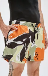 Short de baño con estampado de hojas en tonos naranja, marrón, verde y blanco. Tiene cintura elástica con cordón ajustable y bolsillos laterales.