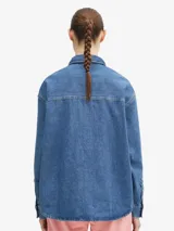 Camisa de denim azul de Carhartt WIP, de corte holgado, manga larga, cuello clásico y cierre frontal con botones. Tiene un bolsillo en el pecho con etiqueta con el logo de la marca.