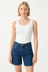 Musculosa blanca de algodón con cuello redondo y detalle de tachas plateadas en el escote.