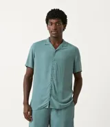 Camisa celeste de viscosa, corte regular, con cuello clásico, botones frontales, mangas cortas y bolsillo en el pecho.