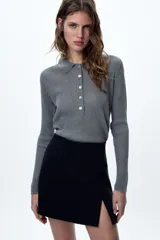 Falda pantalón negra de tiro alto con abertura frontal y cierre lateral con cremallera oculta.