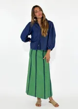 Pollera larga de jean azul con corte acampanado y costuras verticales en color ladrillo.