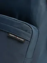 Mochila azul marino de poliéster con logo de Tommy Hilfiger en el frente. Cuenta con múltiples bolsillos, correas ajustables y acolchadas, asa superior y cierre de doble cremallera.