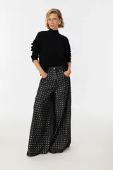 Pantalón wide leg gris con tachas plateadas en el frente.