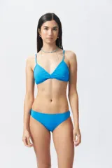 Top de bikini blanco con diseño cruzado en el escote, breteles finos regulables y cierre con broche en la espalda.