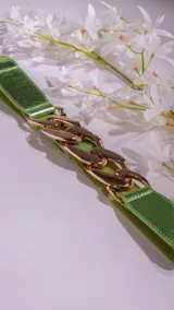 Cinto verde con detalle de cadena dorada, confeccionado en material simil cuero.
