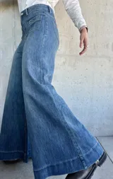 Pantalón de jean azul de corte pata de elefante, con bolsillos frontales tipo parche.
