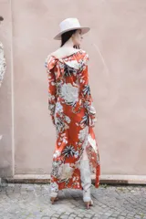 Vestido largo de seda color ladrillo con estampado de tigres, flores y palmeras. Tiene escote en V, mangas largas y tajos laterales.