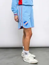 Short deportivo azul marino con ribetes blancos y rojos, y escudo del Club Nacional de Football bordado en la pierna derecha.