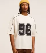 Remera de corte boxy color crema con estampa del número 96 en el frente y detalles en negro en cuello y mangas.